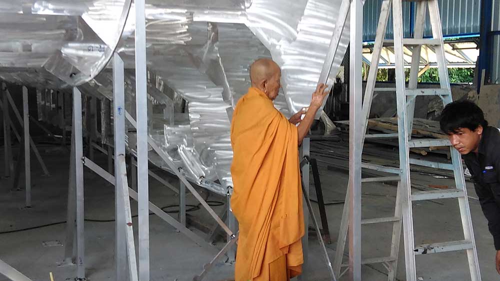 Buddist monk marking the boat with gold paint and gold leaf